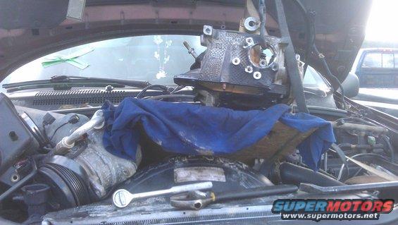 engine part being lifted out of an engine bay, tools on the radiator