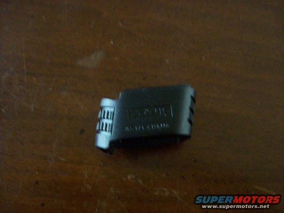 Black plastic part with ridges on one end and embossed text on the side