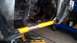 1993 Mercury Tracer - Close-up view of a vehicle's undercarriage, showing engine components and a yellow support bar.