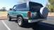 1982 Ford Bronco - This Ford Bronco is parked in a lot with a grassy field and trees in the background.
