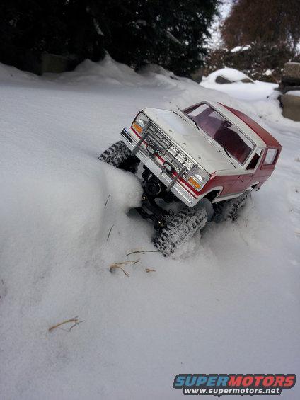 Remote control toy truck with red body and white top driving in snow