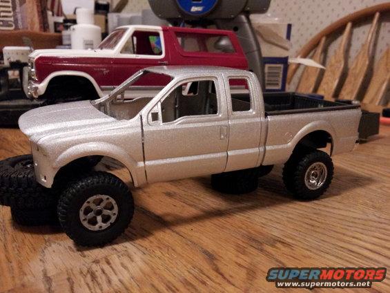 Silver pickup truck model with lifted suspension and spare tires