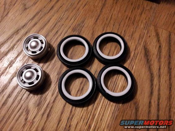 Model car wheels and tires with white sidewalls on a wooden surface