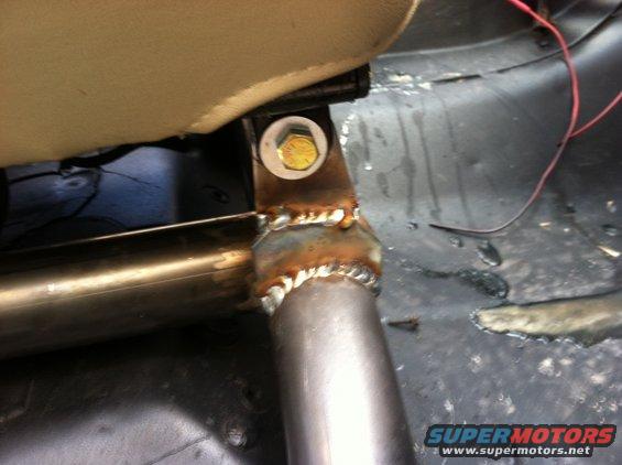 Close-up of a welded metal bracket attached to a seat mount, with wiring visible