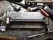 1964 Mercury Monterey - A metal suspension control arm with rubber bushings is shown on a workbench with various tools.