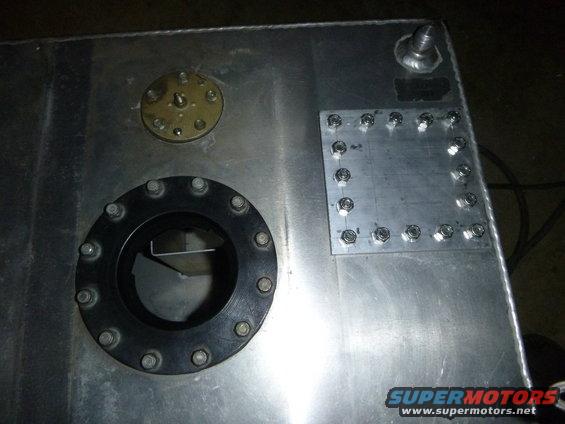 Aluminum fuel tank with a large circular fitting and a smaller circular fitting, plus a bolted plate