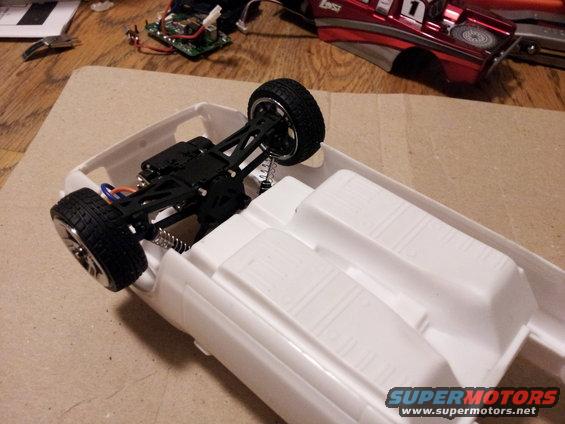 White model car chassis with black suspension and wheels