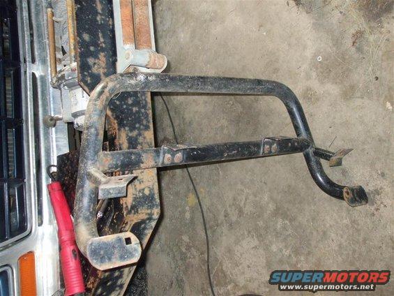 Black metal front bumper guard with two horizontal bars, mounted on a rusty frame