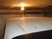 1979 Ford Bronco - The roof of a white vehicle is visible inside a garage, illuminated by a bare light bulb.