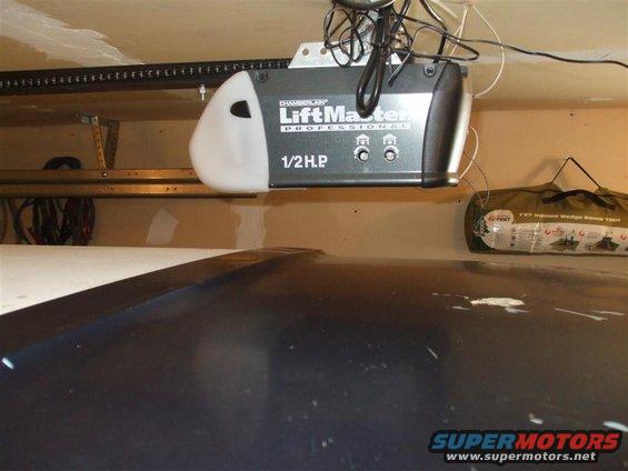 Dark car hood with white paint specks and a LiftMaster Professional 1/2 HP garage door opener above