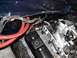 1979 Ford Bronco - Close-up of engine bay components, including red hoses and electrical wiring. Text on hose is visible.