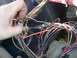 1979 Ford Bronco - Close-up of a tangled automotive wiring harness, with a hand adjusting connections.