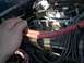 1979 Ford Bronco - Close-up of an engine bay with a hand manipulating wires near the fuel injection system.