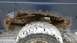 1979 Ford Bronco - The underside of a dark blue vehicle shows significant rust damage around the rear wheel well, which is covered in snow.