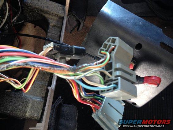 Wiring harness with multiple colored wires connected to gray plastic connectors inside a vehicle