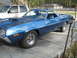 1972 Ford Ranchero - This blue 1972 Ford Ranchero features a prominent hood scoop and is parked next to a white SUV.