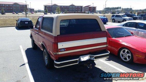 Red and tan 1989 Ford Bronco rear view with white stripe detail
