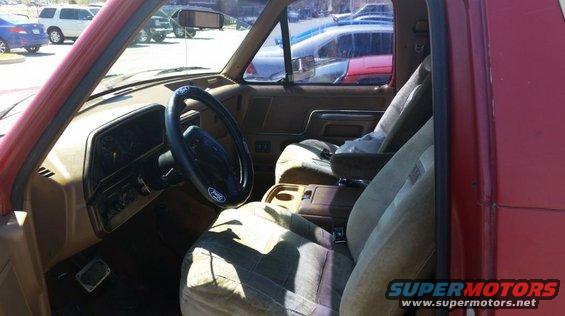 Interior of a red 1989 Ford Bronco, showing the dashboard, steering wheel, and front seats
