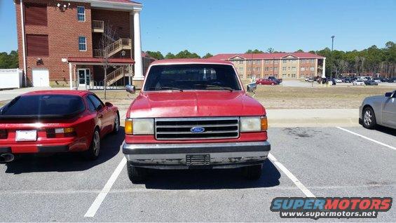 Red Ford F-Series truck, front view, parked in a lot. Grille and headlights indicate an early 1987-1991 model