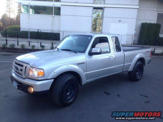 Silver Ford Ranger pickup truck parked in front of a modern building