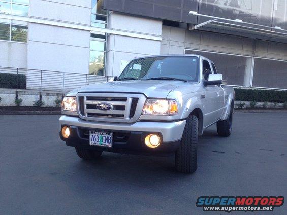 Silver Ford Ranger pickup truck, front view, parked in front of a modern building