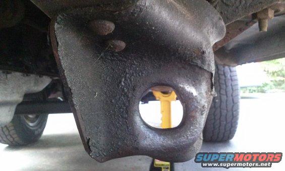 Close-up of a rusty underbody suspension part with a large hole