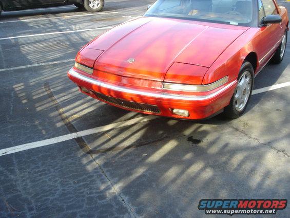Red coupe with pop-up headlights and chrome trim, parked in a lot