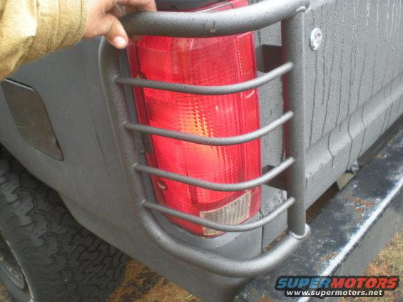 Dark gray SUV rear tail light with protective bars, tire visible