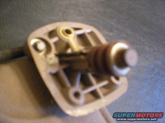 Close-up of a tan plastic automotive part with a metal rod and brown ribbed cylinder