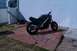 1986 Honda Interceptor - A black motorcycle is parked on a patio with a lawnmower nearby.