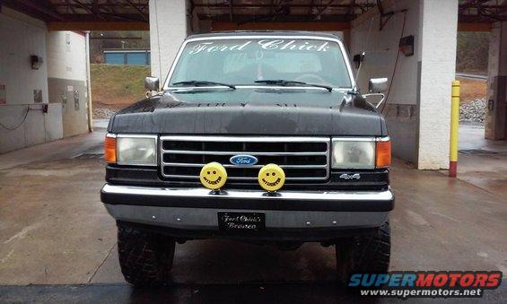 Black Ford F-Series truck front view, with smiley face fog lights and 'Ford Chick' banner on windshield
