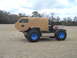 1992 Ford Bronco - A custom-built vehicle with large tires and a boxy tan body sits in a grassy field under a cloudy sky.