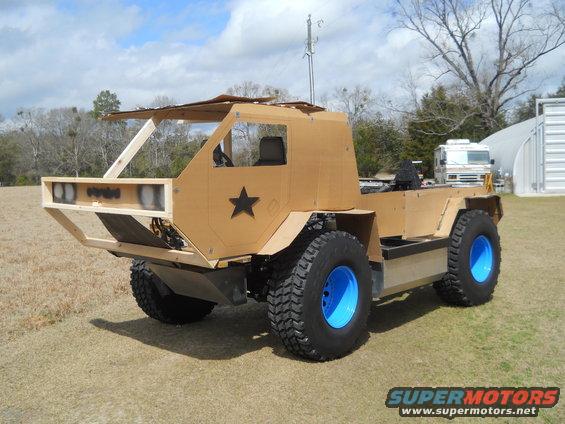 Custom vehicle with cardboard body, black star emblem, and bright blue rims, viewed from the front-right