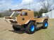 1992 Ford Bronco - A homemade vehicle with a cardboard exterior and blue wheels sits on a grassy field under a cloudy sky.