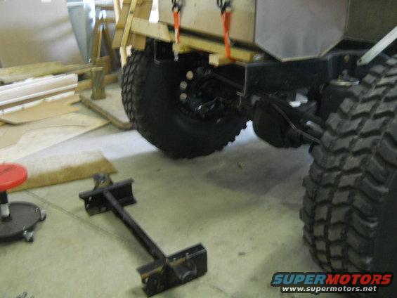 Rear axle and large tire of a vehicle in a workshop, with wooden framing above
