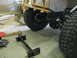 1992 Ford Bronco - Close-up view of the rear axle and tire of a vehicle being worked on in a garage, with wooden construction elements visible.