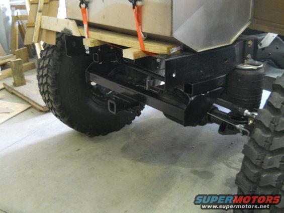 Truck chassis with large off-road tires, air suspension, and a wooden platform secured with straps