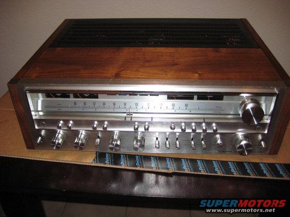 Vintage stereo receiver with wood grain trim and silver faceplate, tuning dial and numerous knobs
