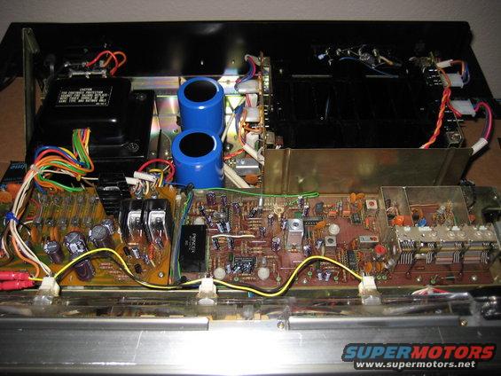 Inside of a car stereo with circuit boards, wires, and capacitors