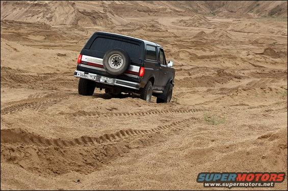 1987 Ford Bronco driving on sand dunes, rear view. License plate P368BC 192