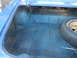 1967 Pontiac GTO - The trunk of a blue car shows its carpeted interior and a spare tire with a gold rim.
