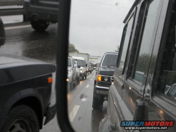 Traffic jam on a wet road. A black Ford Bronco is visible in the lane next to the camera car