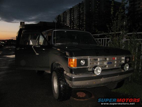 Black 1987 Ford Bronco with driver door open, parked at dusk