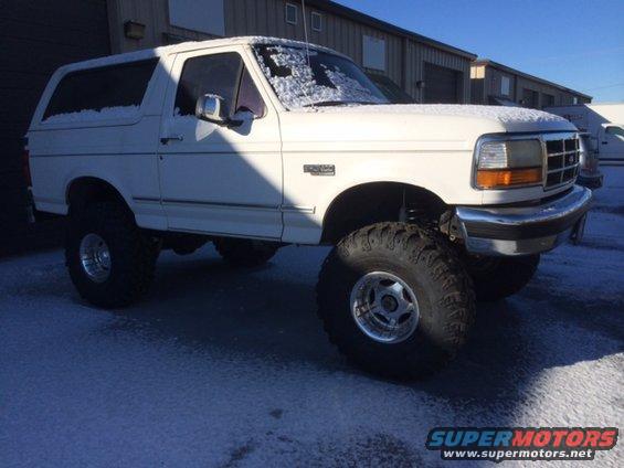 White Ford Bronco with lifted suspension and large tires parked in snow