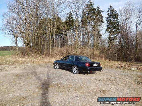 Black 2003 Mercury Marauder parked on dirt lot with trees in background