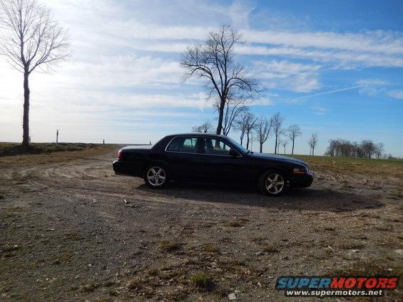 Black 2003 Mercury Marauder parked on a dirt road under a cloudy sky