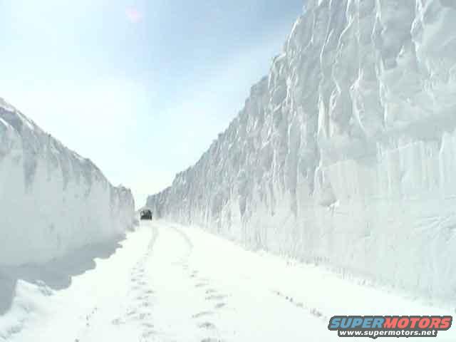 Vehicle driving on a road with very high snowbanks on either side