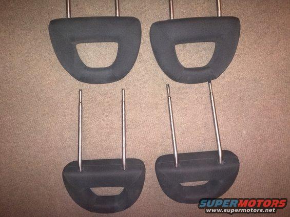 Four black car headrests with metal posts, laid out on a carpeted surface