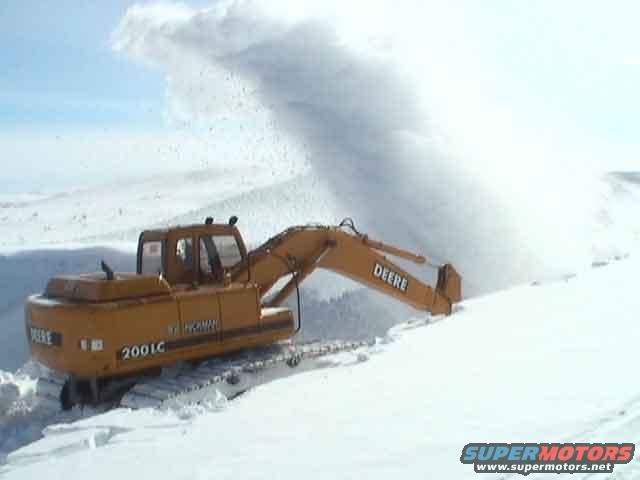 John Deere 200LC excavator with tracks clearing a large amount of snow