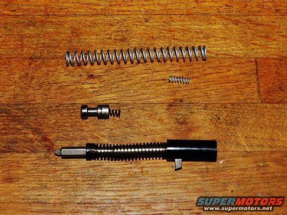Gun barrel assembly with springs and pin on wooden surface